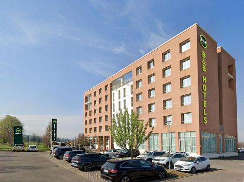 a large building with cars parked in a parking lot at B&B HOTEL Remilia in Reggio Emilia