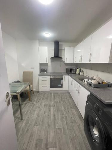 a kitchen with white cabinets and a washer and dryer at en-suite rooms available for short term in Huddersfield