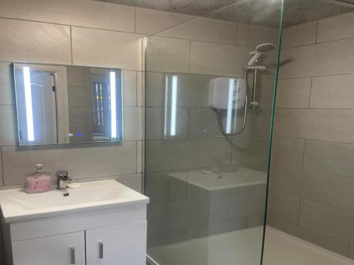 a bathroom with a shower with a sink and a mirror at en-suite rooms available for short term in Huddersfield