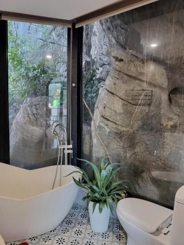 a bathroom with a large window and a tub and a toilet at Catba Garden Camellia in Cat Ba