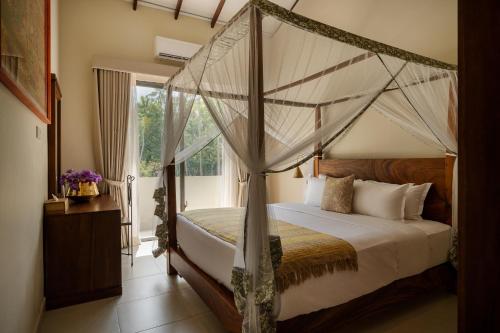 a bedroom with a canopy bed and a window at Rekawa Wellness Resort in Tangalle