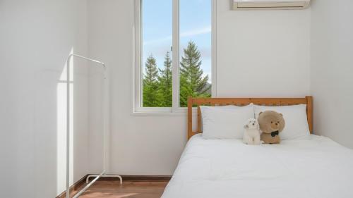 a bed with two teddy bears sitting on it at Chuncheon Dogandstay in Chuncheon