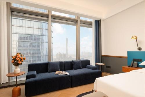 a living room with a blue couch in front of a window at The Protons Guangzhou in Guangzhou