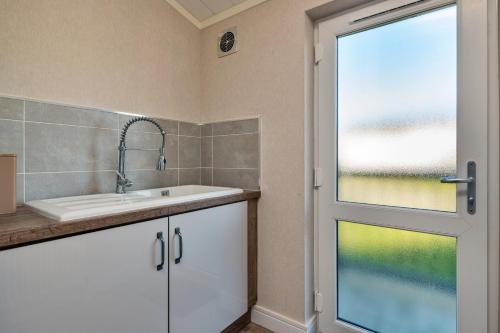a bathroom with a sink and a window at Finest Retreats - Pembroke Luxury Lodge in Bourn