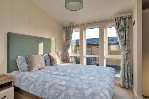 a bedroom with a bed and a large window at Finest Retreats - Pembroke Luxury Lodge in Bourn