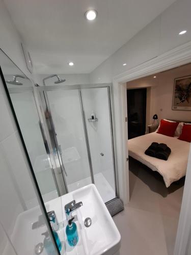 a bathroom with a sink and a shower and a bed at Elegant Garden Flat - Raynes Park in Raynes Park