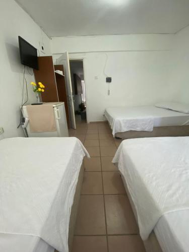 a hotel room with two beds and a tv at denge pansiyon in Datca