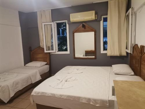 a room with two beds and a mirror and windows at denge pansiyon in Datca
