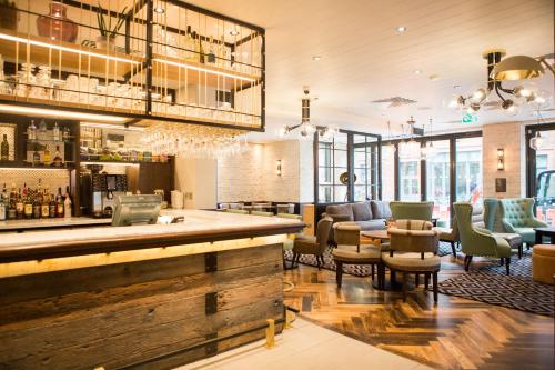 a restaurant with a bar with chairs and tables at hub London - King's Cross in London