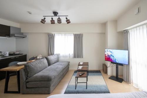a living room with a couch and a flat screen tv at Hotel HIRAKU RYUKYU -STYLE- in Naha