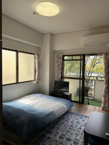 a bedroom with a bed and a desk and windows at Peace Wing 3C in Hiroshima