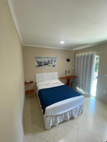 a bedroom with a bed with a blue blanket at Linda casa em Tarituba in Paraty
