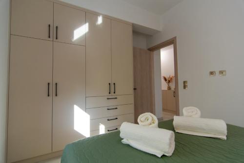 a bedroom with a green bed with white cabinets and towels at Amelia Summer Homes in Pérdika