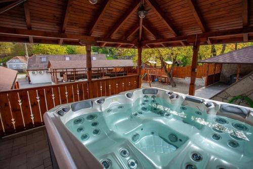 a jacuzzi tub on a patio with a deck at Nagyon Vadon vendégház in Háromhuta