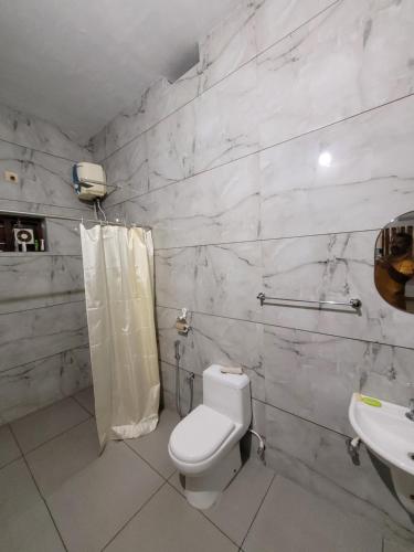 a white bathroom with a toilet and a sink at Akalapuzha Homestay in Kozhikode