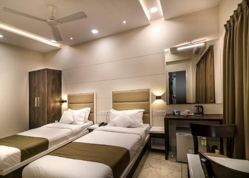 a hotel room with three beds and a desk at Hotel Royal Treat Surat in Surat