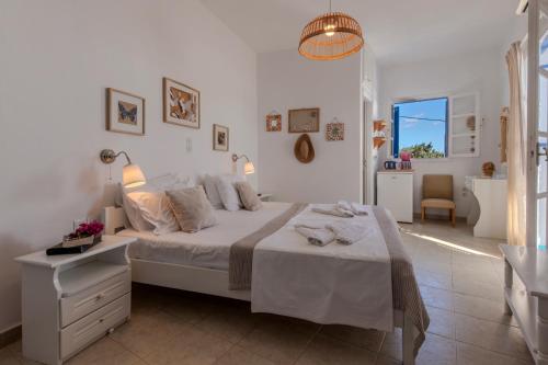 a white bedroom with a bed and a bathroom at Heliotropio Studios & Apartments in Pollonia