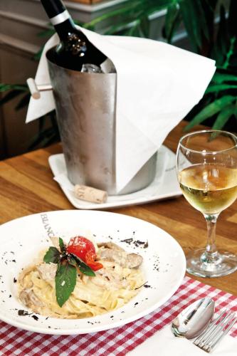 a plate of pasta on a table with a bottle of wine at Casa Bianca Hotel in Denizli