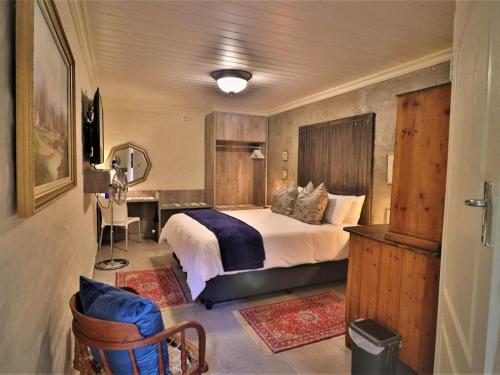 a bedroom with a bed and a desk in a room at The Ranch Guesthouse in Potchefstroom