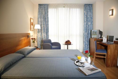 Habitación de hotel con cama, escritorio y TV. en Hotel Mieres del Camino, en Mieres