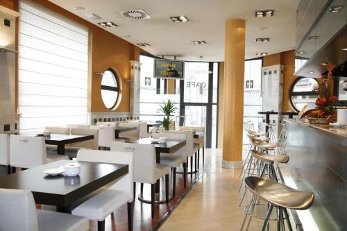 un restaurante con mesas y sillas blancas y una barra en Hotel Mieres del Camino, en Mieres