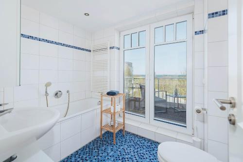 a bathroom with a tub and a toilet and a window at Strandgut in Börgerende-Rethwisch