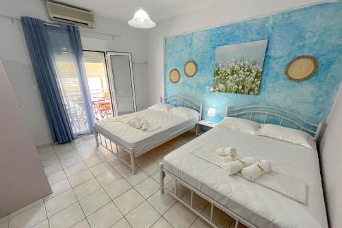 a bedroom with two beds and a blue wall at Villa Leonidas in Nea Vrasna