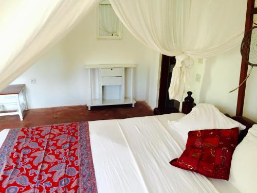 a bedroom with a bed with a red pillow on it at Lazy Beach House in Kiwengwa