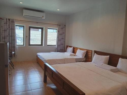 a hotel room with two beds and a television at โรงแรมควีนส์ (Queen) in Ban Tha Kham