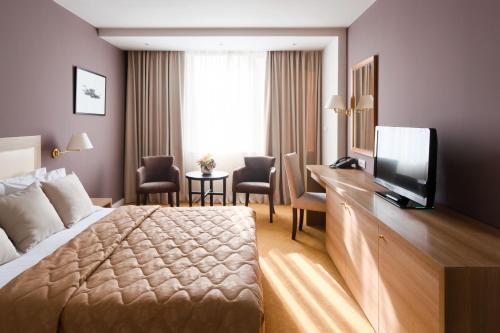 a hotel room with a bed and a flat screen tv at New City Hotel & Restaurant Niš in Niš