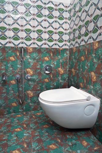 a bathroom with a toilet and a tiled wall at Omji Ashram Jageshwar Mahadev in Varanasi