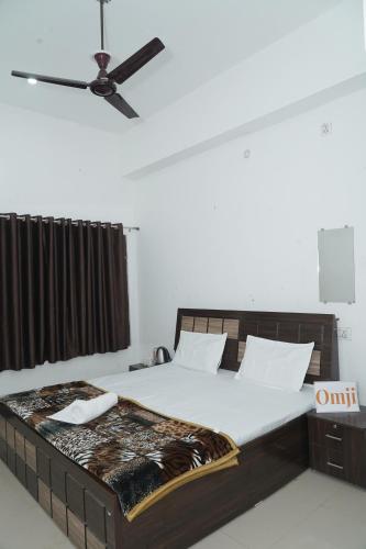 a bedroom with a large bed with a ceiling fan at Omji Ashram Jageshwar Mahadev in Varanasi