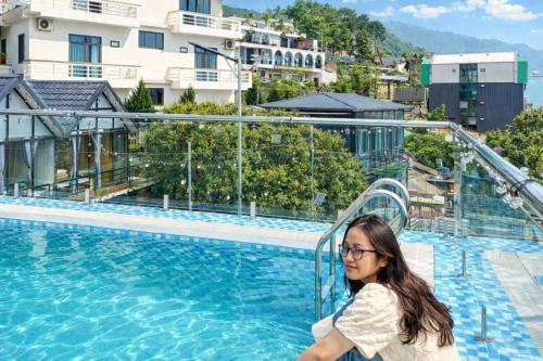 a woman standing next to a swimming pool at Daisy Hotel Tam Dao in Tam Ðảo