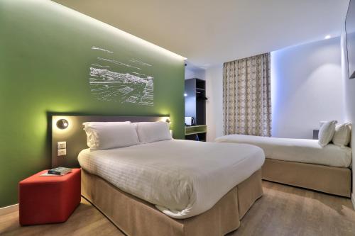 a hotel room with two beds and a red stool at Hôtel Cyano Fréjus-Saint Raphaël in Fréjus