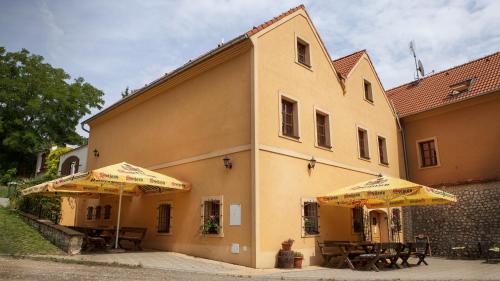two tables and umbrellas in front of a building at Penzion Zatisi in Mikulov