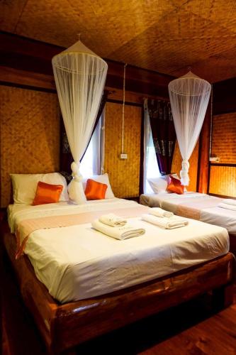 two beds in a room with curtains on them at Le mont pai resort in Pai