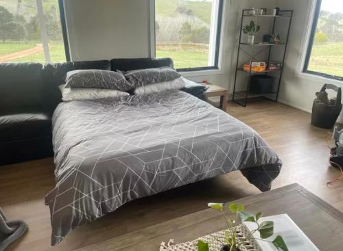a bed with a gray comforter in a living room at BrinCole - Pet-Friendly, Huge Deck with Epic Views & Fire Pit in Bonnie Doon
