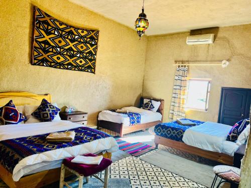 a bedroom with two beds and a chandelier at Hotel Camping Les Roses Des Dunes & Piscine in Merzouga