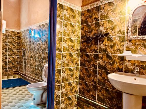 a bathroom with a toilet and a sink at Hotel Camping Les Roses Des Dunes & Piscine in Merzouga