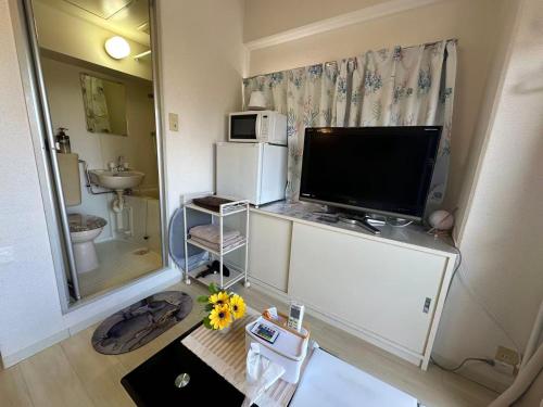 a small room with a television and a refrigerator at Peace Wing 5A in Kami-nagarekawachō