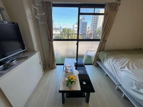 a room with a bed and a table with flowers on it at Peace Wing 5A in Kami-nagarekawachō