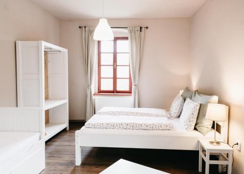 a white bedroom with a bed and a window at Statek Jakubov in Vojkovice