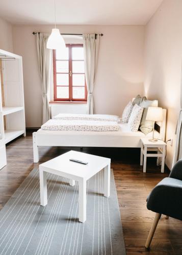 a white room with a bed and a coffee table at Statek Jakubov in Vojkovice