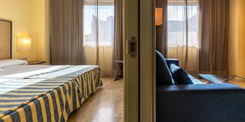 ein Hotelzimmer mit Bett, Sofa und Fenstern in der Unterkunft Apartamentos Vértice Sevilla Aljarafe in Bormujos