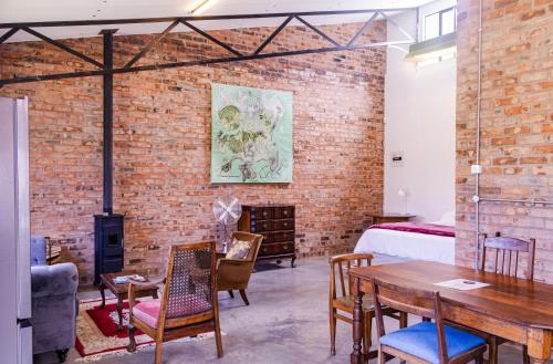 a room with a brick wall and a bed and a table at The Old Mushroom Farm in Howick