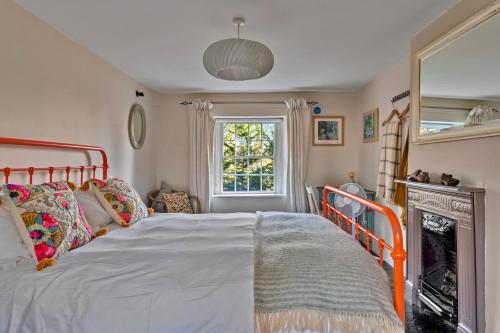 a bedroom with a bed and a fireplace and a window at Finest Retreats - Flittermouse Cottage in Wingfield