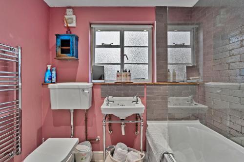 a pink bathroom with a tub and a sink at Finest Retreats - Flittermouse Cottage in Wingfield