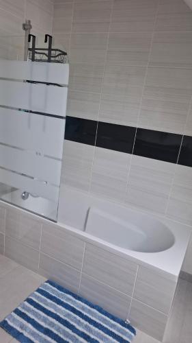 a bathroom with a white tub and a blue rug at Maison Du Bonheur in Erquy
