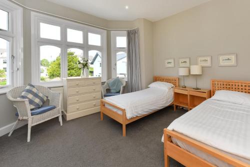 a bedroom with two beds and a chair and windows at 5 Bed in Pwllheli oc-1coedy in Abersoch