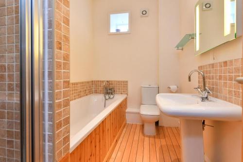 a bathroom with a tub and a toilet and a sink at 5 Bed in Pwllheli oc-1coedy in Abersoch